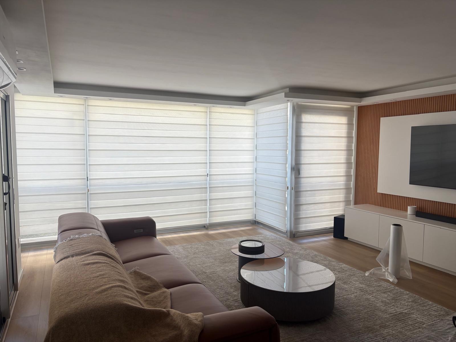 Estar del apartamento Vidal con ventanal amplio, cortinas claras, sofá y sector de televisión